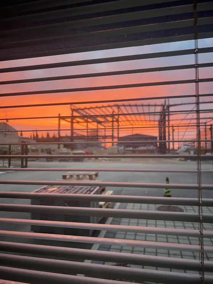 透过百叶窗看到夕阳下的仓库作业区域